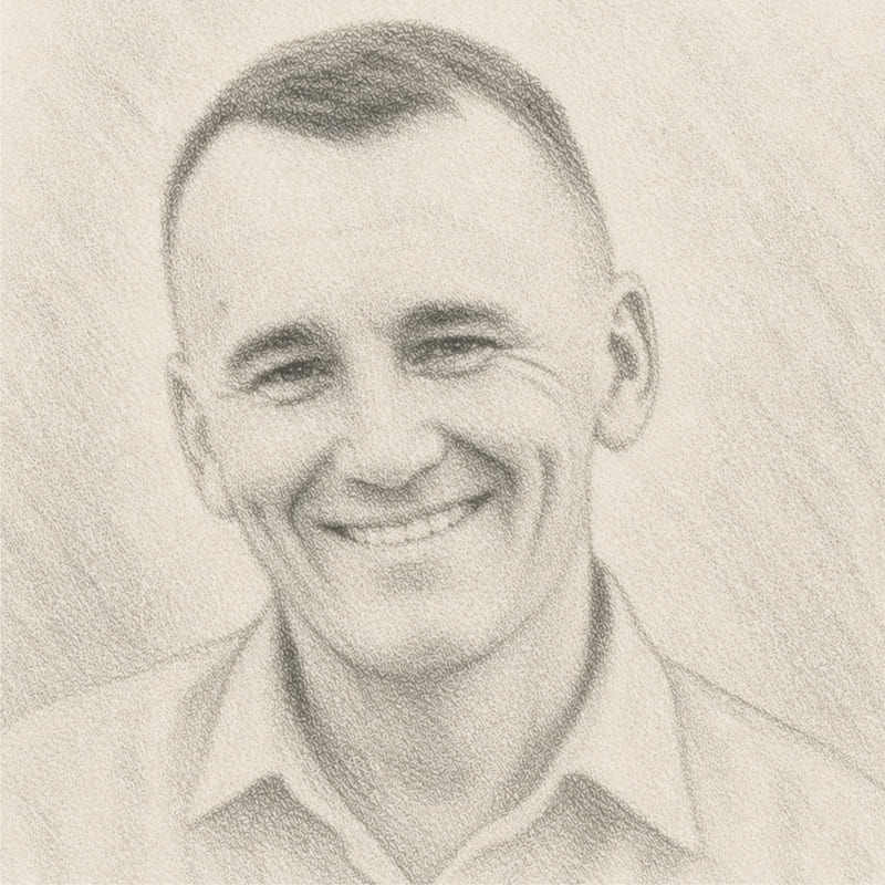 Retrato de Marcelo feito somente à lápis grafite, em tons de cinza, numa leve inclinação de cabeça e com sorriso confiante.